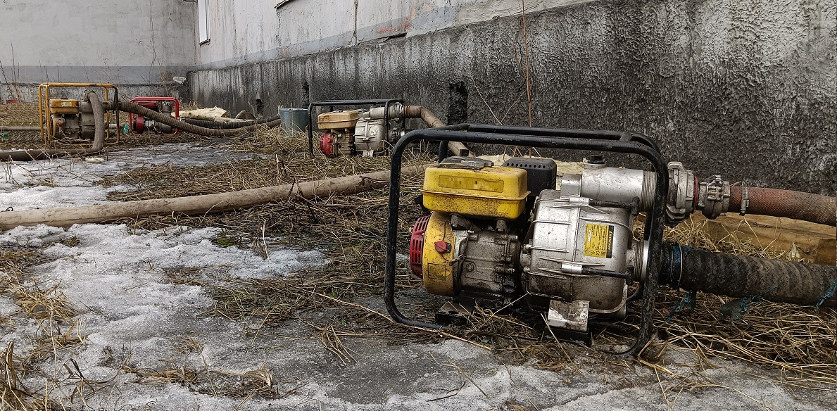 Откачка мотопомпами талой воды из подвала дома в Московской области